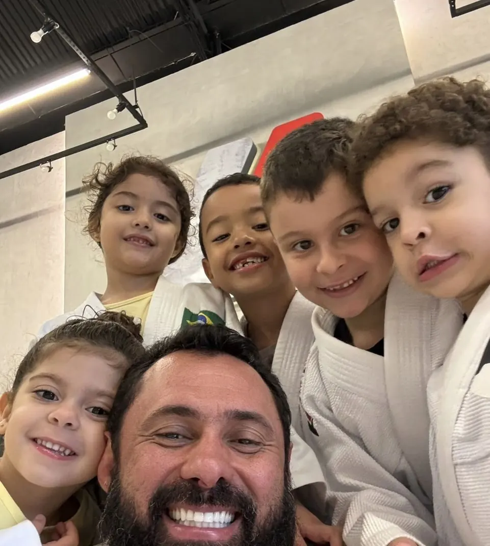 Profesor sonriente con niños en kimono en una selfi